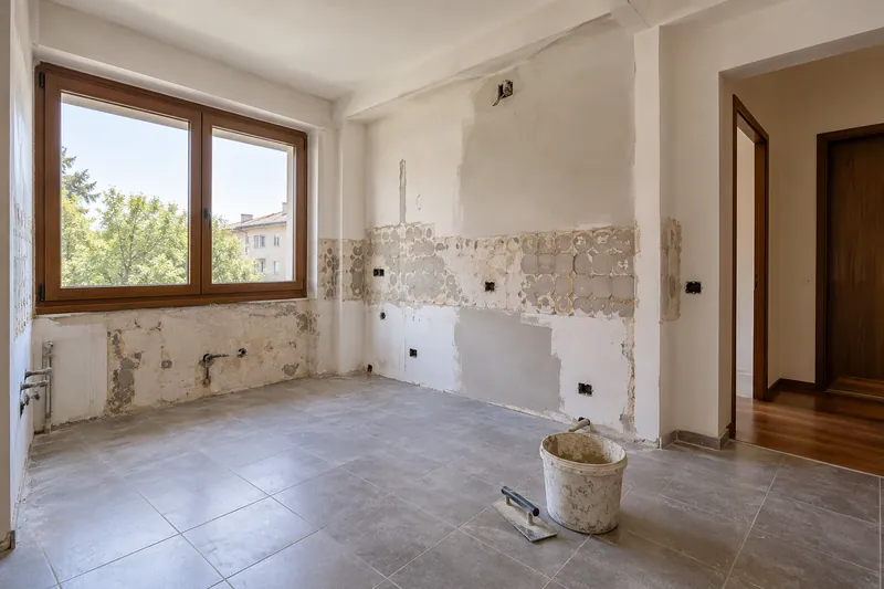 Visualización conceptual IA: Cocina sin muebles con paredes en preparación y zonas de enlucido.